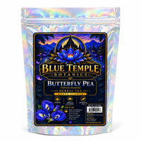 A stand-up pouch of Blue Temple Botany's Butterfly Pea Herbal Tea with an iridescent holographic finish. The front label features a dark blue and black background with a golden temple, a blue lotus flower, and purple butterfly pea flowers.